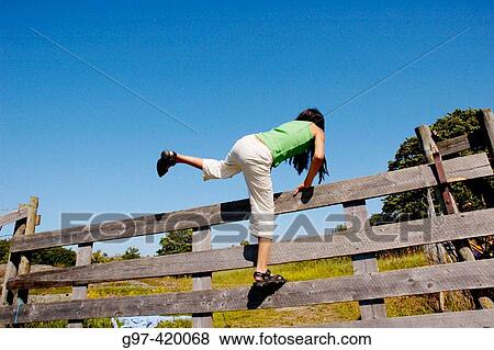 Girl climbing over a fence. View Large Photo Image Stock Photo - Girl climbing over a fence.. Fotosearch