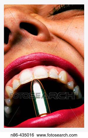 Girl clinching bullet between teeth View Large Photo Image Stock Photograph - Girl clinching bullet between teeth. Fotosearch