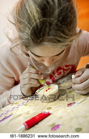 Stock Image - Girl decorating muffin. Fotosearch