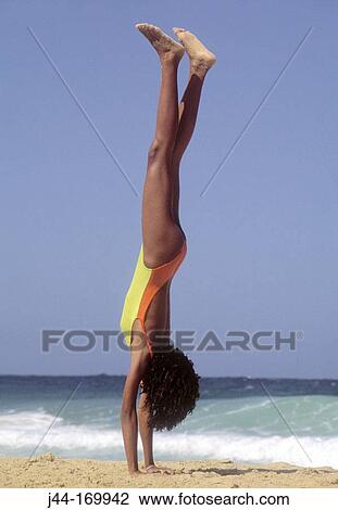Stock Image - Girl doing a hand stand on the beach, Venezuela. Fotosearch