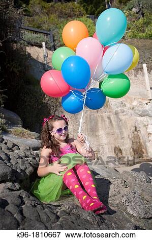 girl dressed up with balloons sitting on rocks View Large Photo Image Stock Photo - girl dressed up with balloons sitting on rocks. Fotosearch