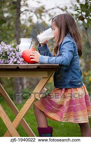 Stock Image - Girl drinking a glass of milk outdoor in the garden. Slovenian countryside.. Fotosearch