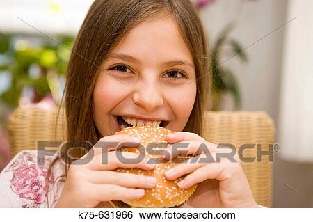 Stock Photograph - Girl eating a hamburger. Fotosearch
