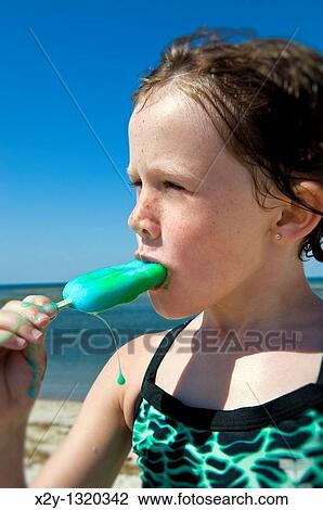Girl eating a popcicle at the beach View Large Photo Image Stock Image - Girl eating a popcicle at the beach. Fotosearch