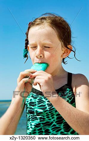 Girl eating a popsicle at the beach View Large Photo Image Stock Image - Girl eating a popsicle at the beach. Fotosearch