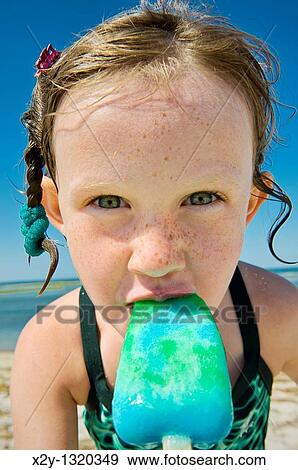 Girl eating a popsicle at the beach View Large Photo Image Stock Photo - Girl eating a popsicle at the beach. Fotosearch