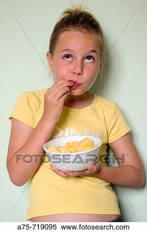 Stock Photography - Girl eating fruit. Fotosearch