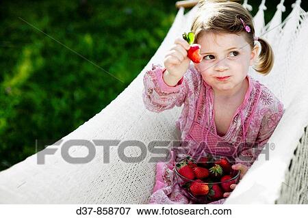Girl eating strawberries on a hammock View Large Photo Image Stock Photo - Girl eating strawberries on a hammock. Fotosearch