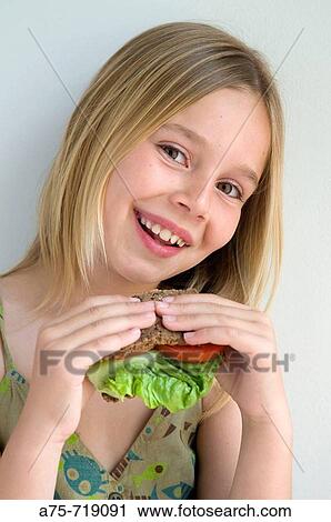 Stock Image - Girl eating vegetable sandwich. Fotosearch