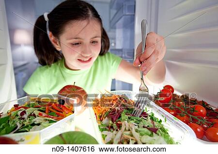 Girl eats salad from the fridge View Large Photo Image Stock Photograph - Girl eats salad from the fridge. Fotosearch