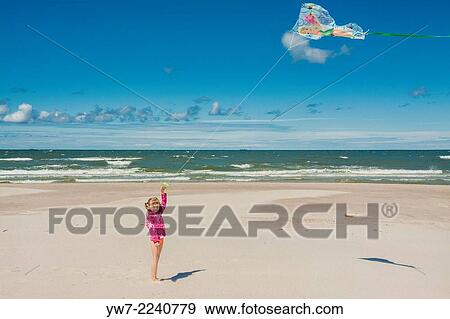 Stock Photo - Girl flying a kite on a beach in Bialogora, Poland.. Fotosearch