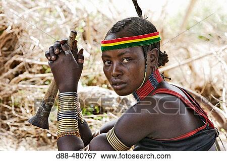 Stock Photo - Girl Hamer tribe. Lower basin of Omo river. Gathering before the fest of the whipping ceremony and the bull jumping. Copper skin with very fine features and wear metal arm and leg bracelets, shells and beads. South Ethiopia.. Fotosearch