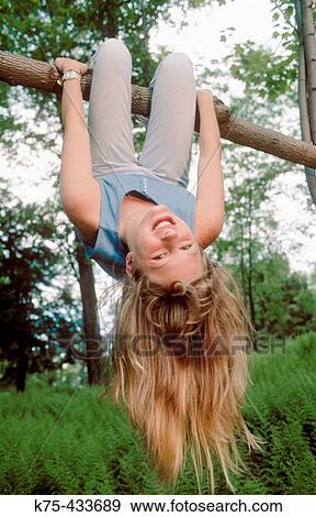 Stock Photo - girl hanging from tree branch. Fotosearch