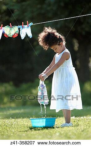 Girl hanging her doll's clothes View Large Photo Image Stock Photo - Girl hanging her doll's clothes. Fotosearch