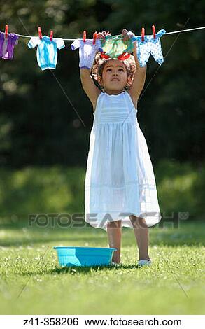 Girl hanging her doll's clothes View Large Photo Image Stock Photograph - Girl hanging her doll's clothes. Fotosearch