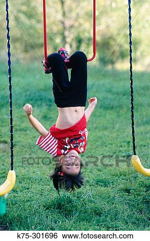 Girl hanging upside down on playset View Large Photo Image Stock Photograph - Girl hanging upside down on playset. Fotosearch