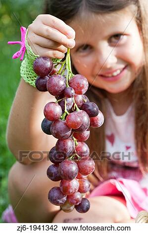 Stock Image - Girl holding a large grape? Cardinal? - Vitis vinifera.. Fotosearch