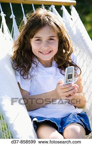 Girl holding a mobile phone smiling outdoors View Large Photo Image Stock Photo - Girl holding a mobile phone smiling outdoors. Fotosearch