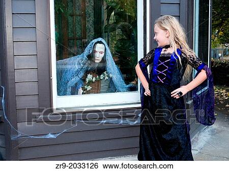 Girl in costume looks at scary witch decoration in window. View Large Photo Image Stock Photograph - Girl in costume looks at scary witch decoration in window.. Fotosearch