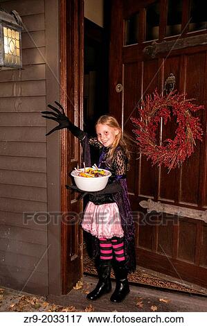 Girl in Halloween costume holds bowl of candy in doorway. View Large Photo Image Stock Photo - Girl in Halloween costume holds bowl of candy in doorway.. Fotosearch