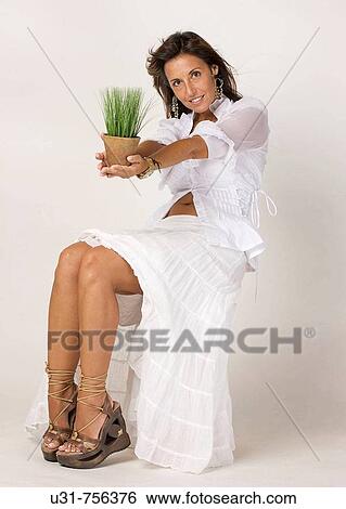 Stock Photograph - Girl in her early 40s offering a plant. Fotosearch