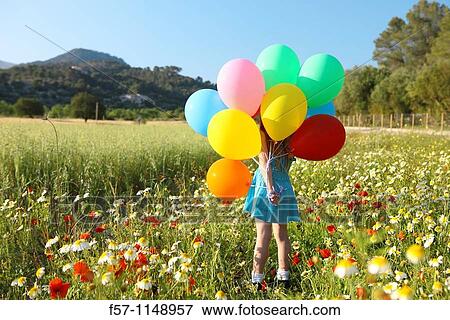 Stock Photo - Girl in meadow with balloons. Fotosearch