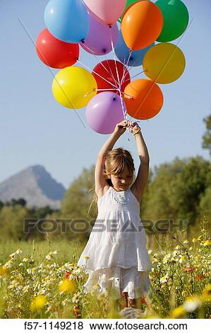 Stock Photo - Girl in meadow with balloons. Fotosearch