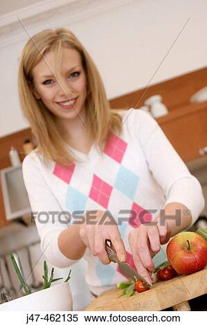 Stock Photography - Girl in the kitchen chopping vegatables selective focus on the food. Fotosearch