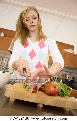 Stock Photograph - Girl in the kitchen chopping vegetables. Fotosearch