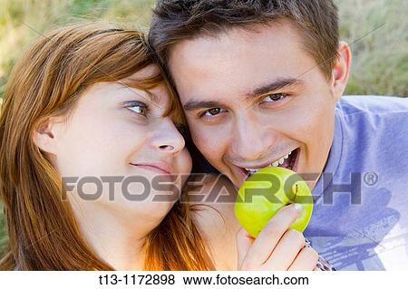 Girl is feeding a boy with a Green apple View Large Photo Image Stock Photo - Girl is feeding a boy with a Green apple. Fotosearch