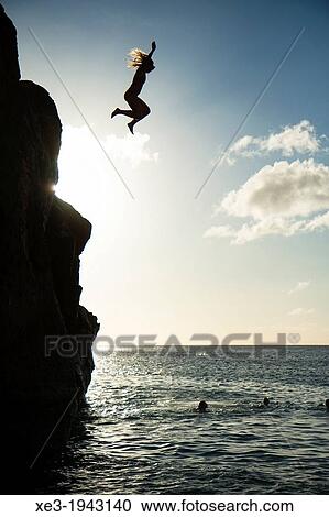 Stock Image - Girl jumping into water, Waimea Bay, Oahu, Hawaii.. Fotosearch