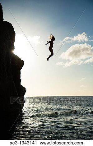 Stock Image - Girl jumping into water, Waimea Bay, Oahu, Hawaii.. Fotosearch