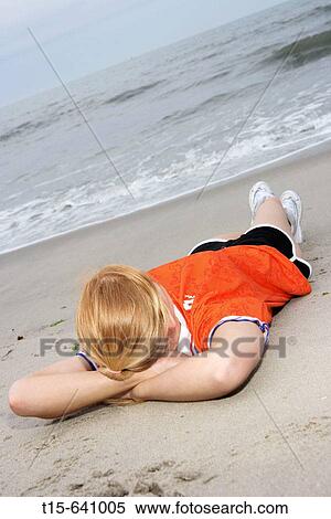 Girl laying on the beach looking at the ocean relaxed and contemplating View Large Photo Image Stock Photography - Girl laying on the beach looking at the ocean relaxed and contemplating. Fotosearch
