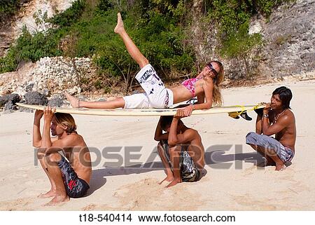 girl leaning on surfboard on three men's head View Large Photo Image Picture - girl leaning on surfboard on three men's head. Fotosearch