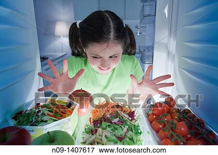 Stock Photo - Girl looks in the fridge. Fotosearch