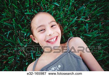Girl lying on grass View Large Photo Image Stock Photo - Girl lying on grass. Fotosearch