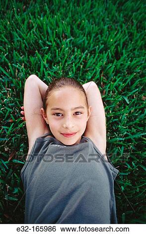 Girl lying on grass View Large Photo Image Stock Photograph - Girl lying on grass. Fotosearch