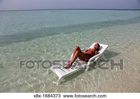 Stock Image - Girl lying on the beach at the seashore, Biyadhoo island, Maldives. Fotosearch