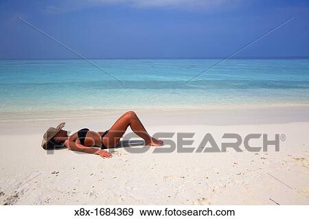 Girl lying on the beach at the seashore, Biyadhoo island, Maldives View Large Photo Image Stock Photo - Girl lying on the beach at the seashore, Biyadhoo island, Maldives. Fotosearch