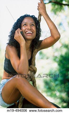 Stock Photograph - girl on a swing rope on cell phone. Fotosearch