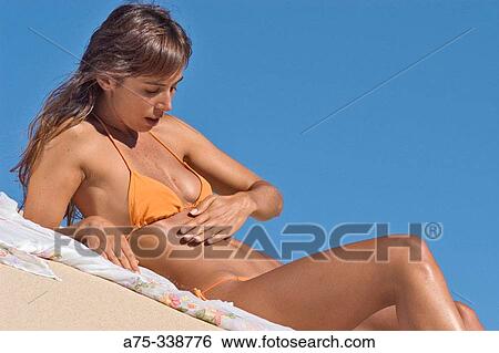 Girl on the beach putting on cream View Large Photo Image Stock Photograph - Girl on the beach putting on cream. Fotosearch