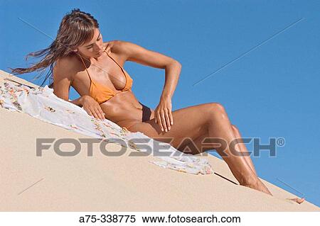 Stock Photography - Girl on the beach putting on cream. Fotosearch