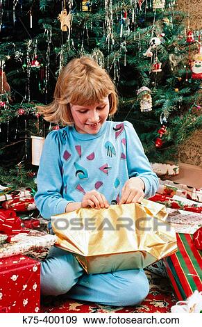 Stock Photo - Girl opening Christmas present. Fotosearch