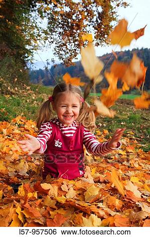 Stock Photograph - girl playing in pile of leaves, fall Zuerich, Switzerland. Fotosearch