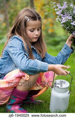 Stock Photography - Girl playing in the garden with recently picket bouquet of asters and vintage milk can. Slovenian countryside.. Fotosearch