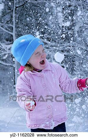 Stock Photo - girl playing in the snow with a snowball headed towards her. Fotosearch