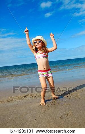 Stock Image - girl playing on sandy beach, Sutherland, Scotland. Fotosearch