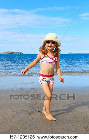 Stock Photograph - girl playing on sandy beach, Sutherland, Scotland. Fotosearch