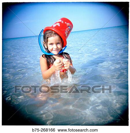 Girl playing with a bucket in the water View Large Photo Image Stock Photograph - Girl playing with a bucket in the water. Fotosearch