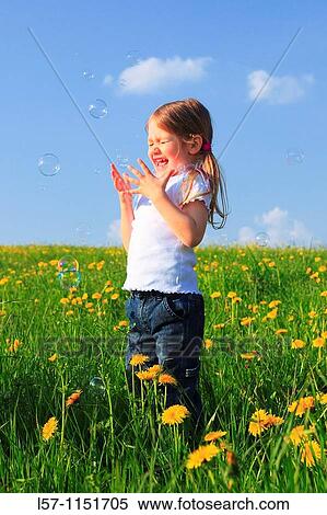 Stock Photography - girl playing with bubbles in field of Dandelions, Zuercher Oberland, Zuerich, Switzerland. Fotosearch